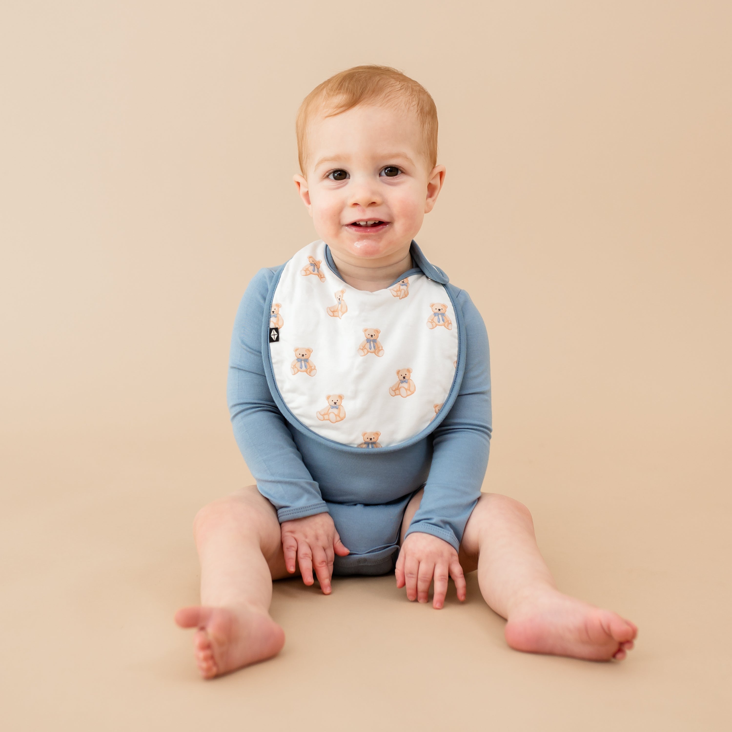 Young toddler wearing Cushy Bib in Teddy Bear with slate bodysuit 