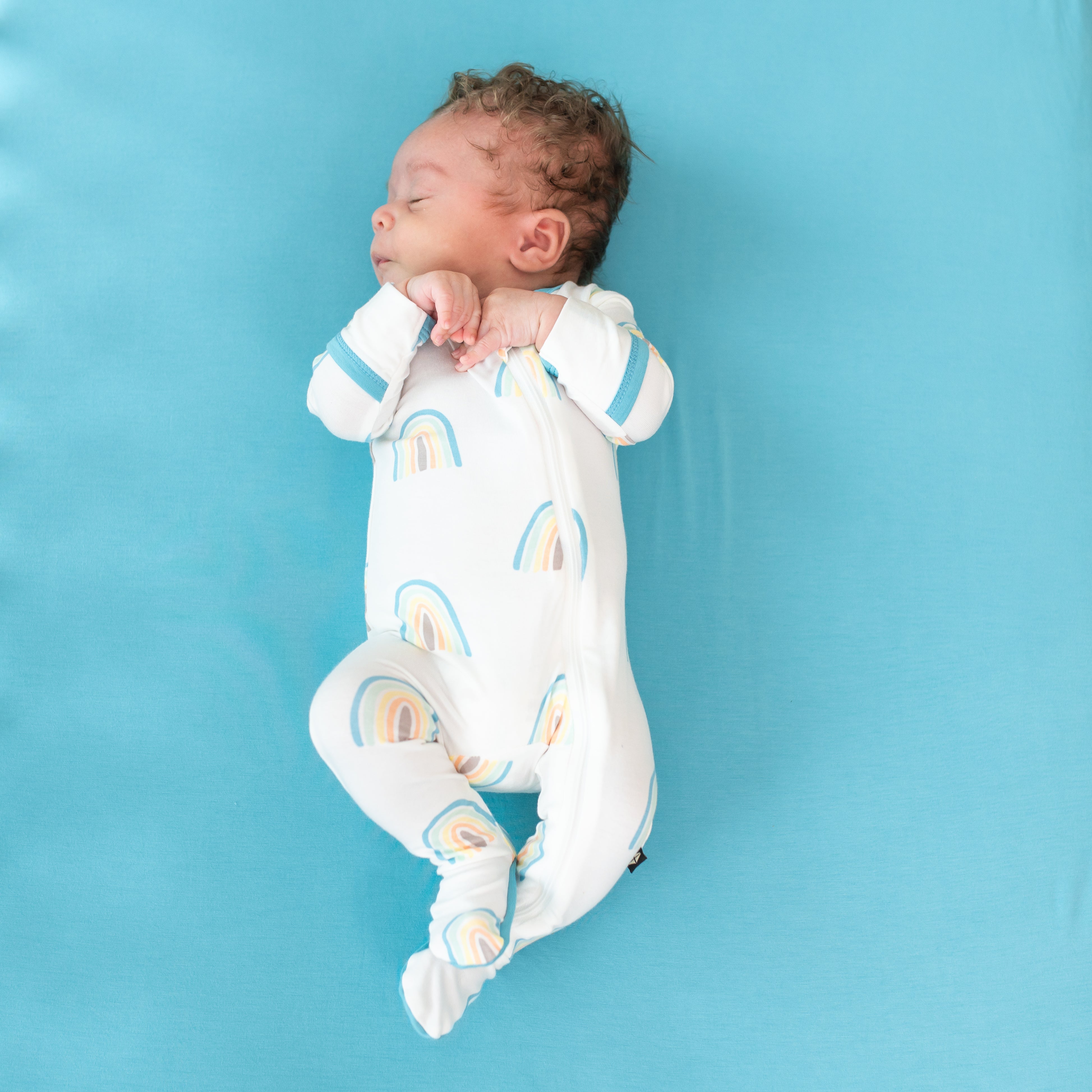 Baby sleeping in Zippered Footie in Makai Rainbow