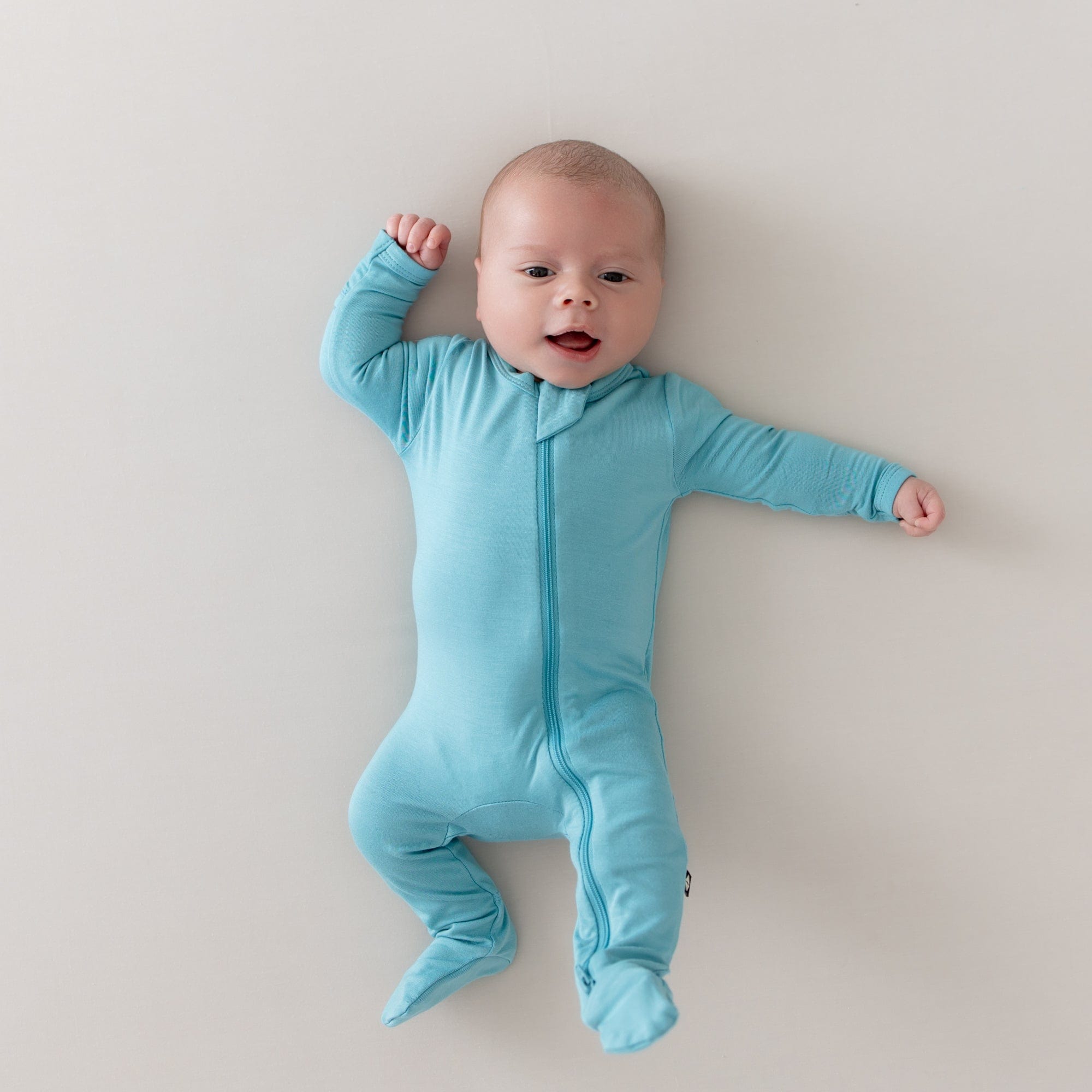 Baby wearing zippered footie in makai blue