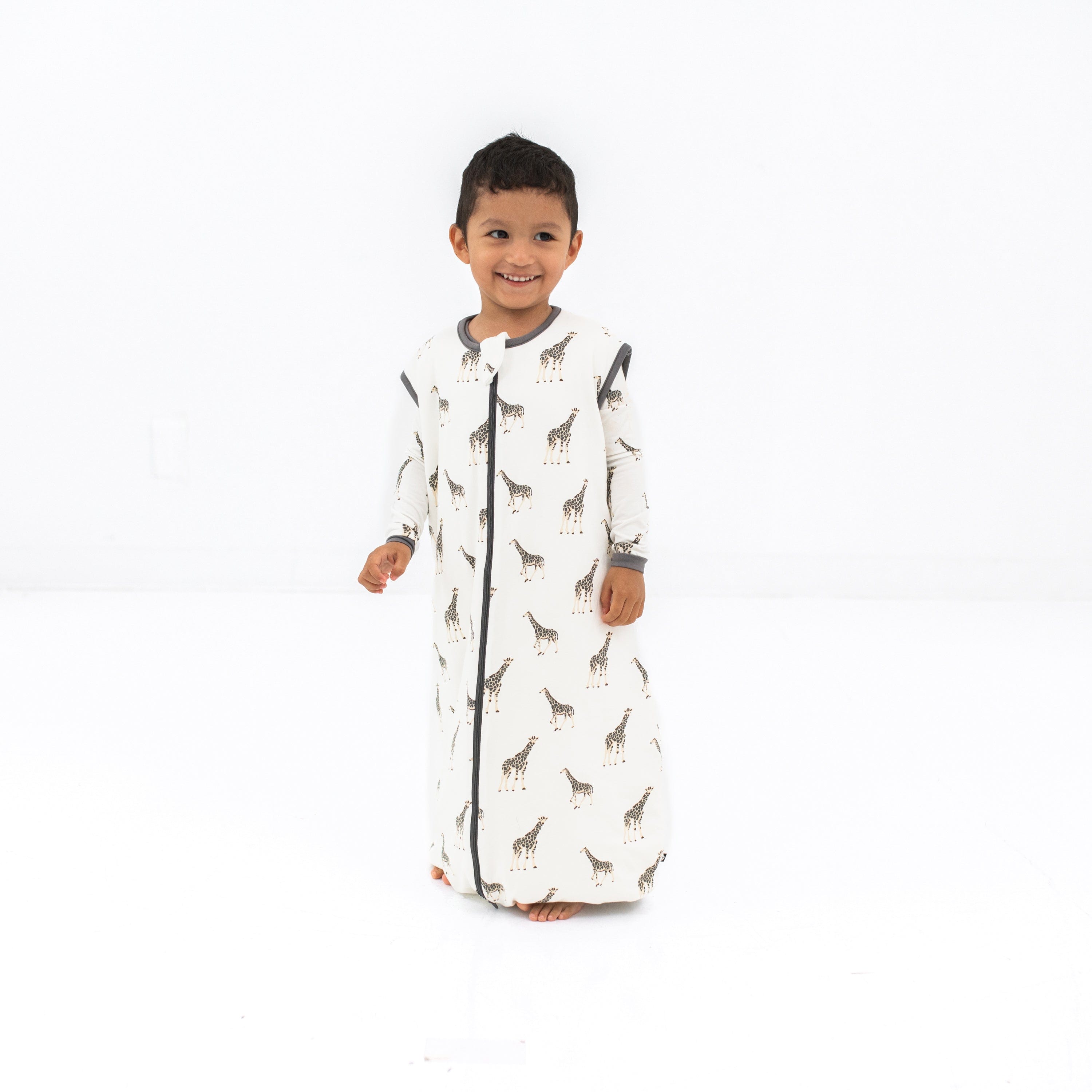 Child model smiling wearing the Sleep Bag Walker in Giraffe 1.0