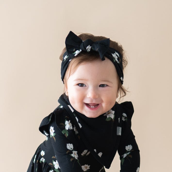 Infant wearing Kyte Baby Bow in Small Magnolia on Midnight