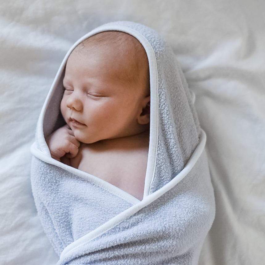 Infant wrapped in Kyte Baby bamboo terry Hooded Bath Towel in Storm with Cloud Trim