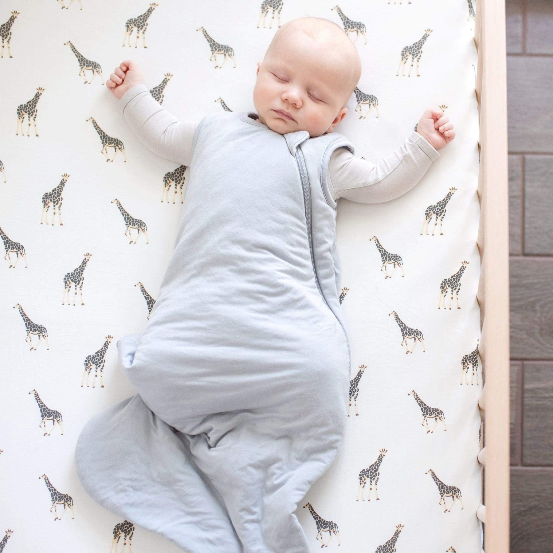 Baby sleeping in Kyte Baby Sleep Bag in Storm 2.5 on a Giraffe Crib Sheet