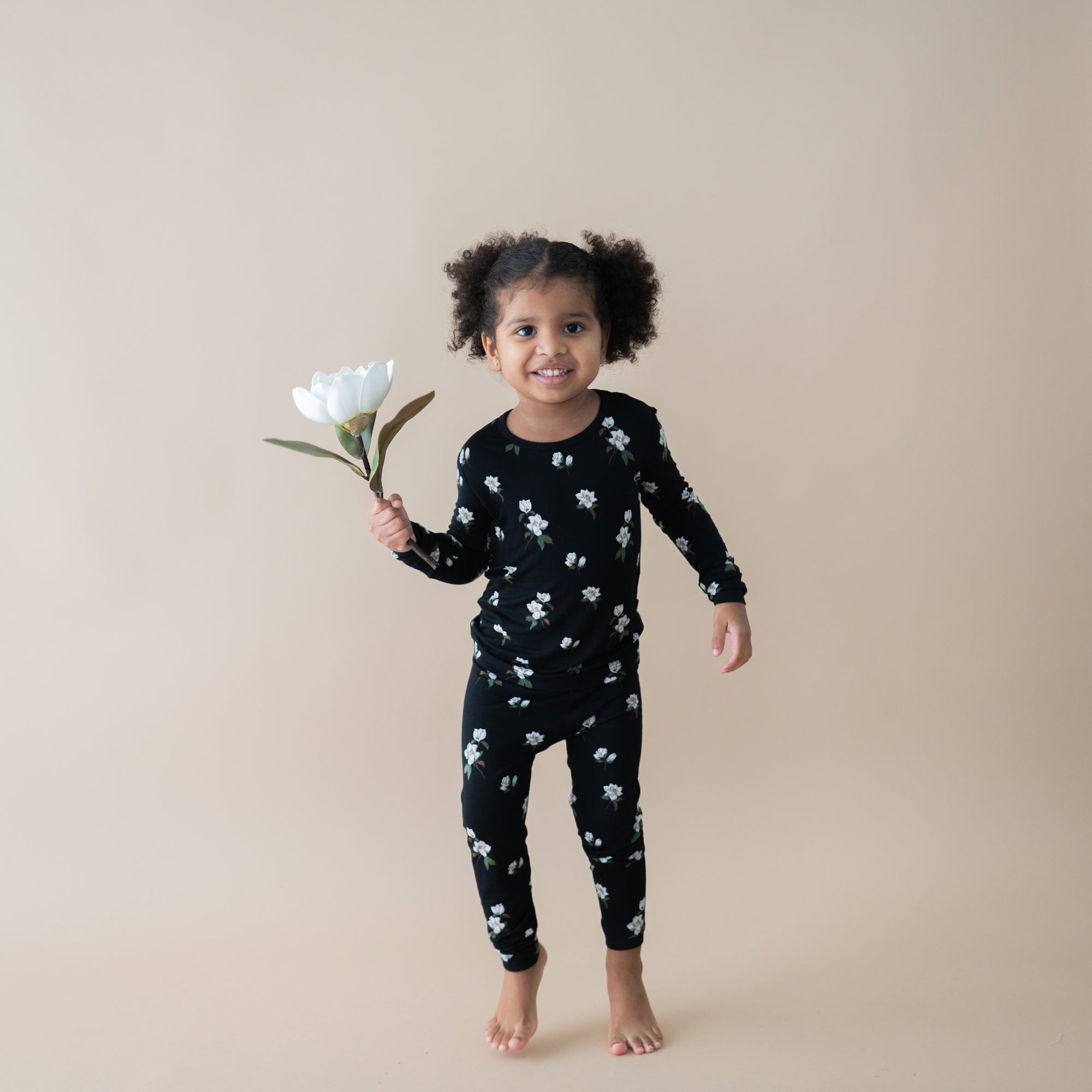 Toddler wearing Kyte Baby Long Sleeve Pajamas in Small Magnolia on Midnight